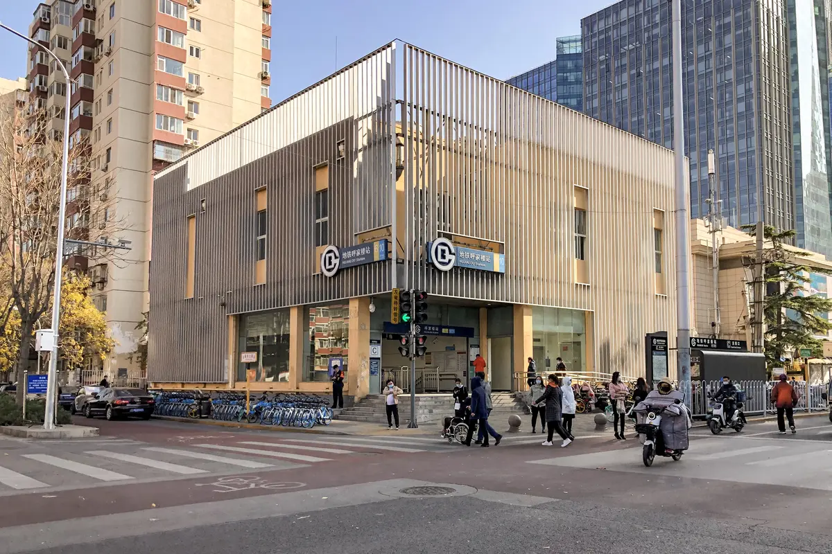 Exit C of Hujialou subway station in Beijing, a two-storey building with a metal-slat facade and the Line 6 and Line 10 signs